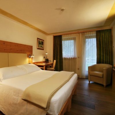Camera d’albergo accogliente con letto matrimoniale, scrivania e poltrona vicino alla finestra. Camera d'albergo accogliente con letto matrimoniale, scrivania e poltrona vicino alla finestra.